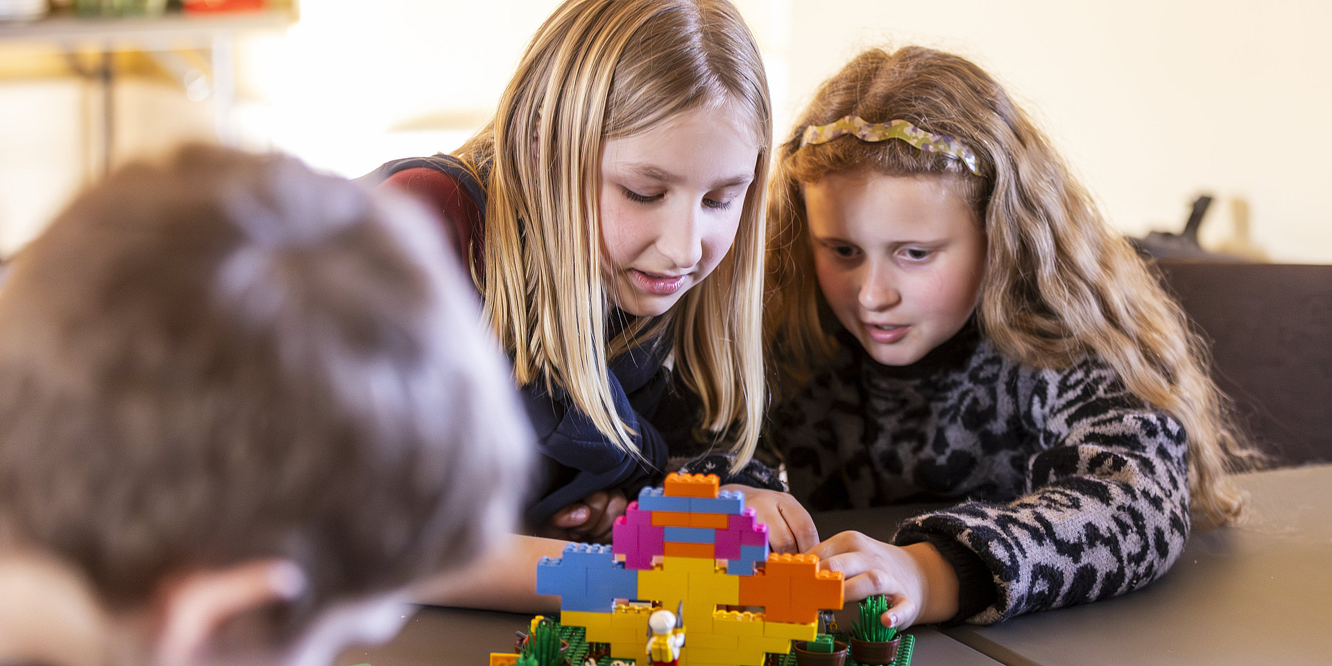 Two girls build a model with Lego bricks.