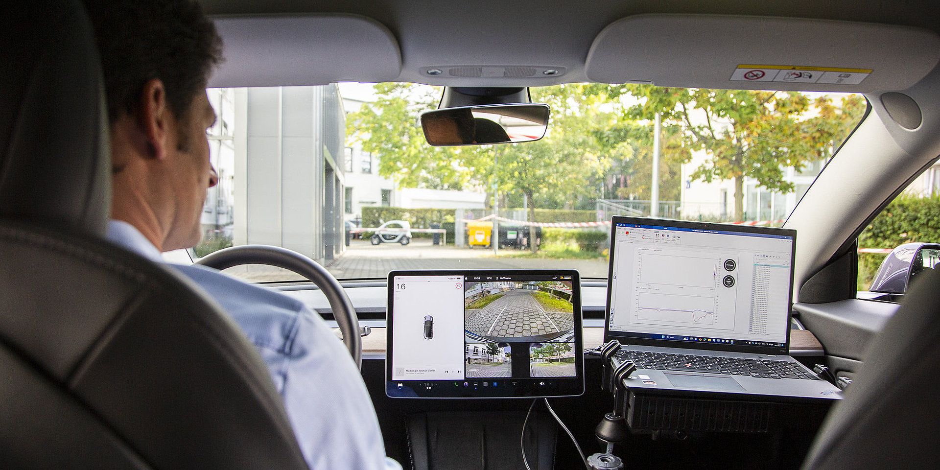 Person sitzt im Auto, während Fahrdaten ausgewertet werden.