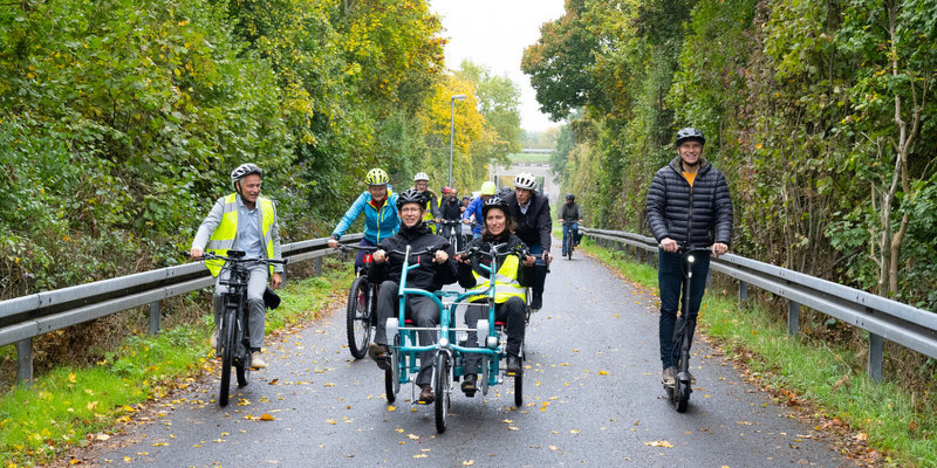 Gruppe von Radfahrenden mit Professor Jürgen Follmann, die auf einer Überführung bergauf radeln