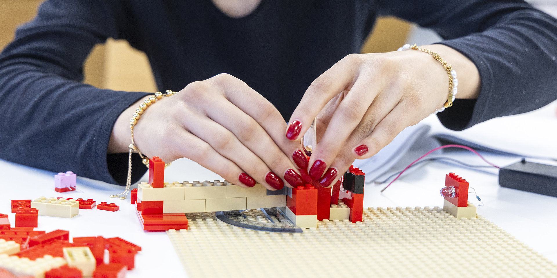 Weibliche Hände bauen ein Modell aus Lego.