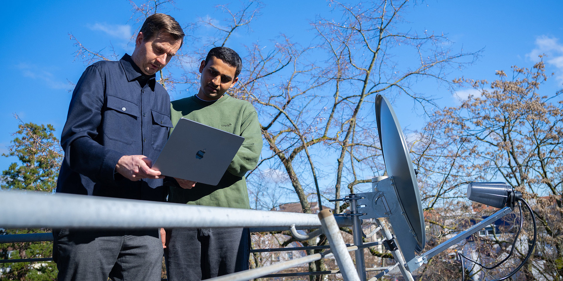 Professor Valentin and student Vedant Vedant are pictured standing next to the satellite dish on a balcony at the Faculty of Computer Science.