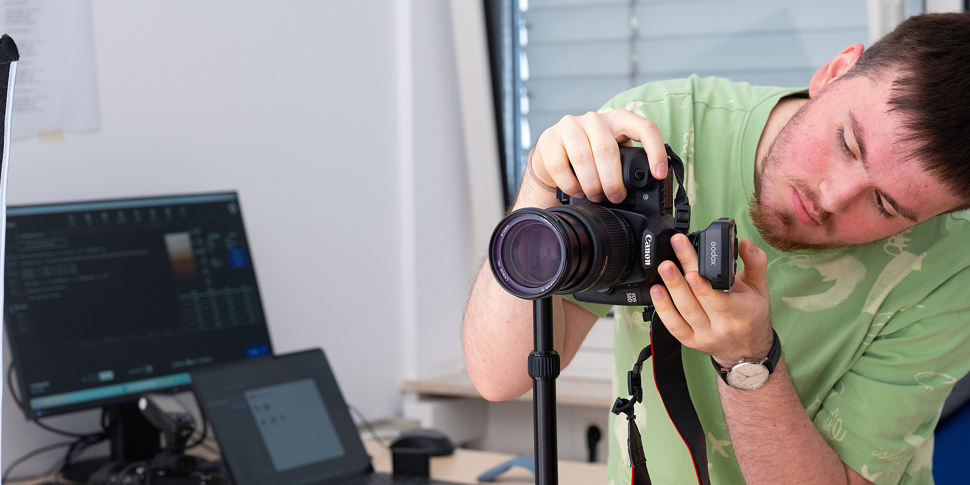 Paul Kibler adjusts a camera on a tripod in the workspace.