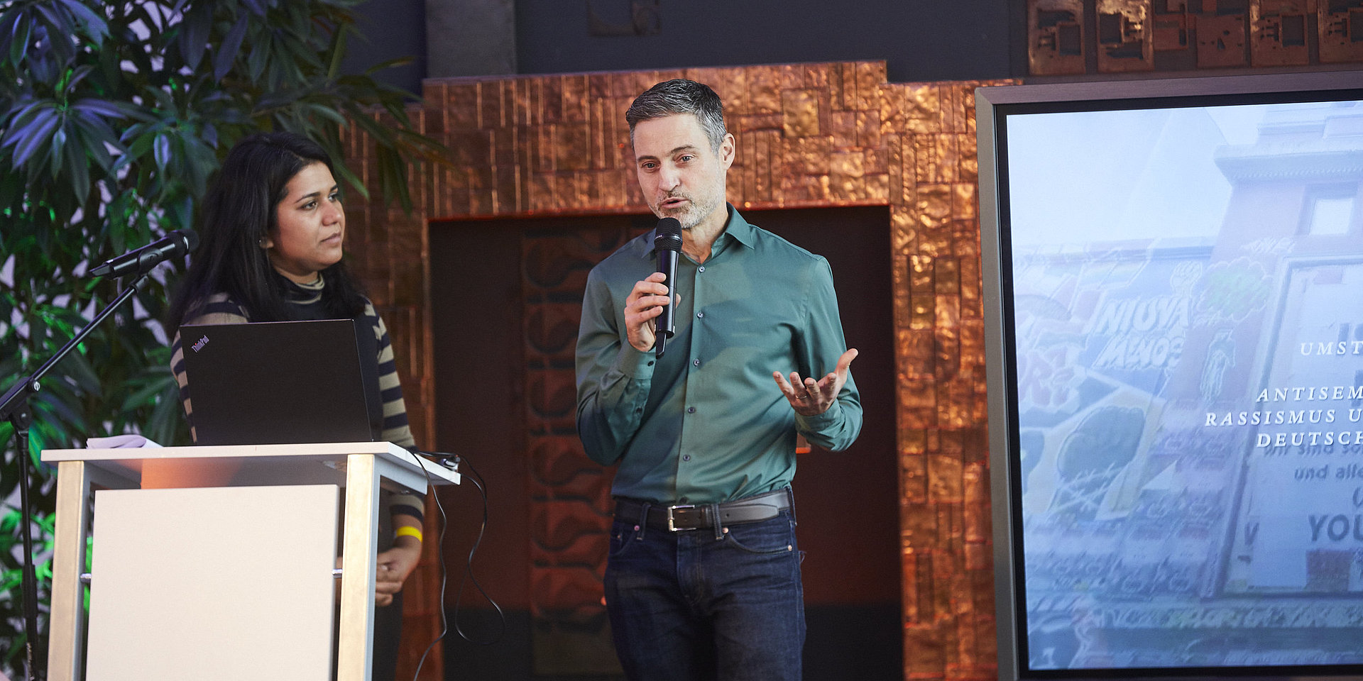 Meron Mendel und Saba-Nur Cheema stehen auf dem Podium