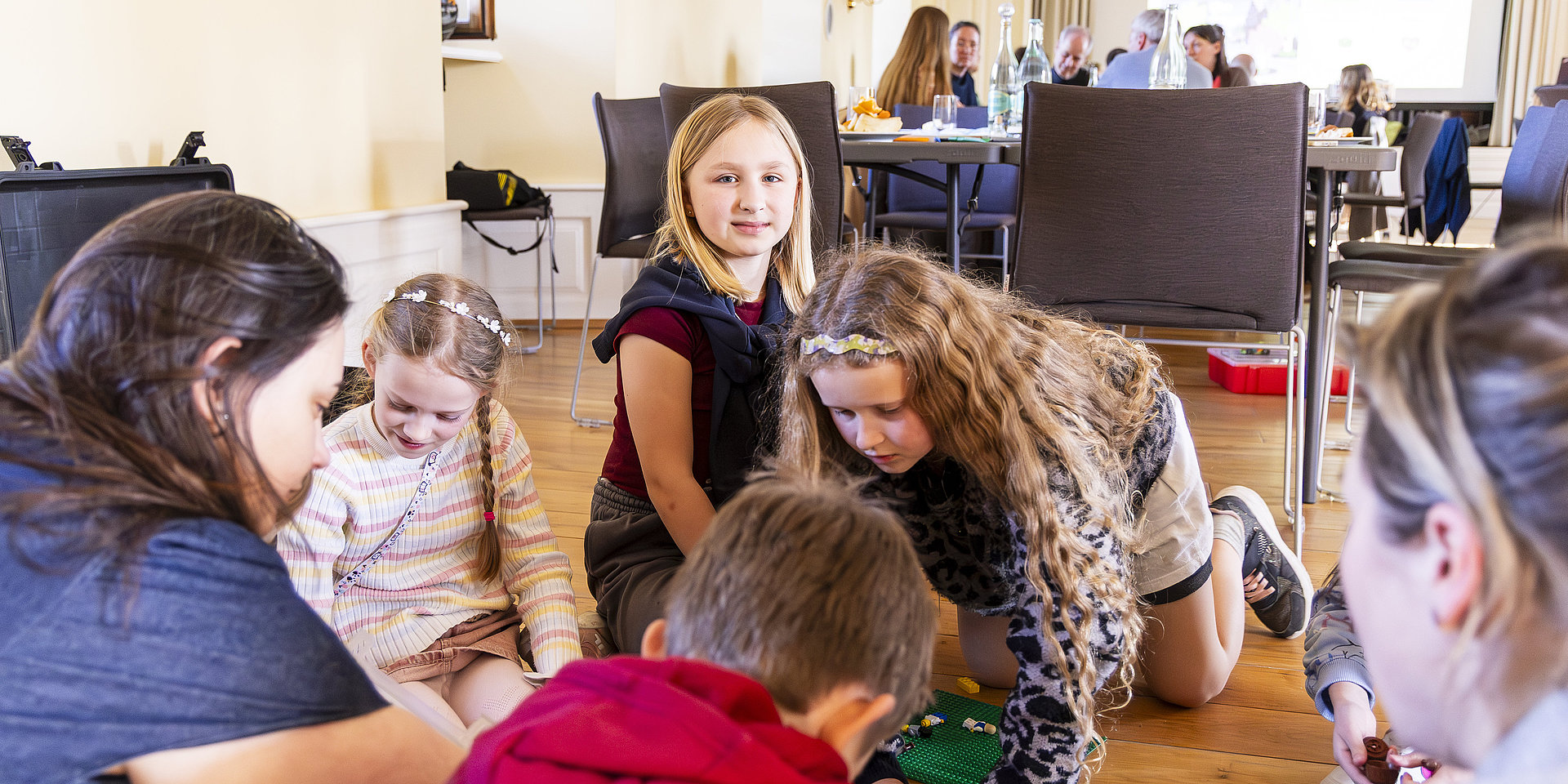 Kinder knien im Rathausaal auf dem Boden und zeichnen und beschreiben ihre Entwürfe für den Platz der Kinderrechte. 