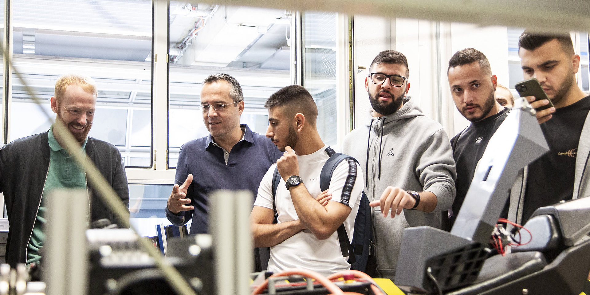 Professor zeigt Studierenden die Automobilwerkstatt.