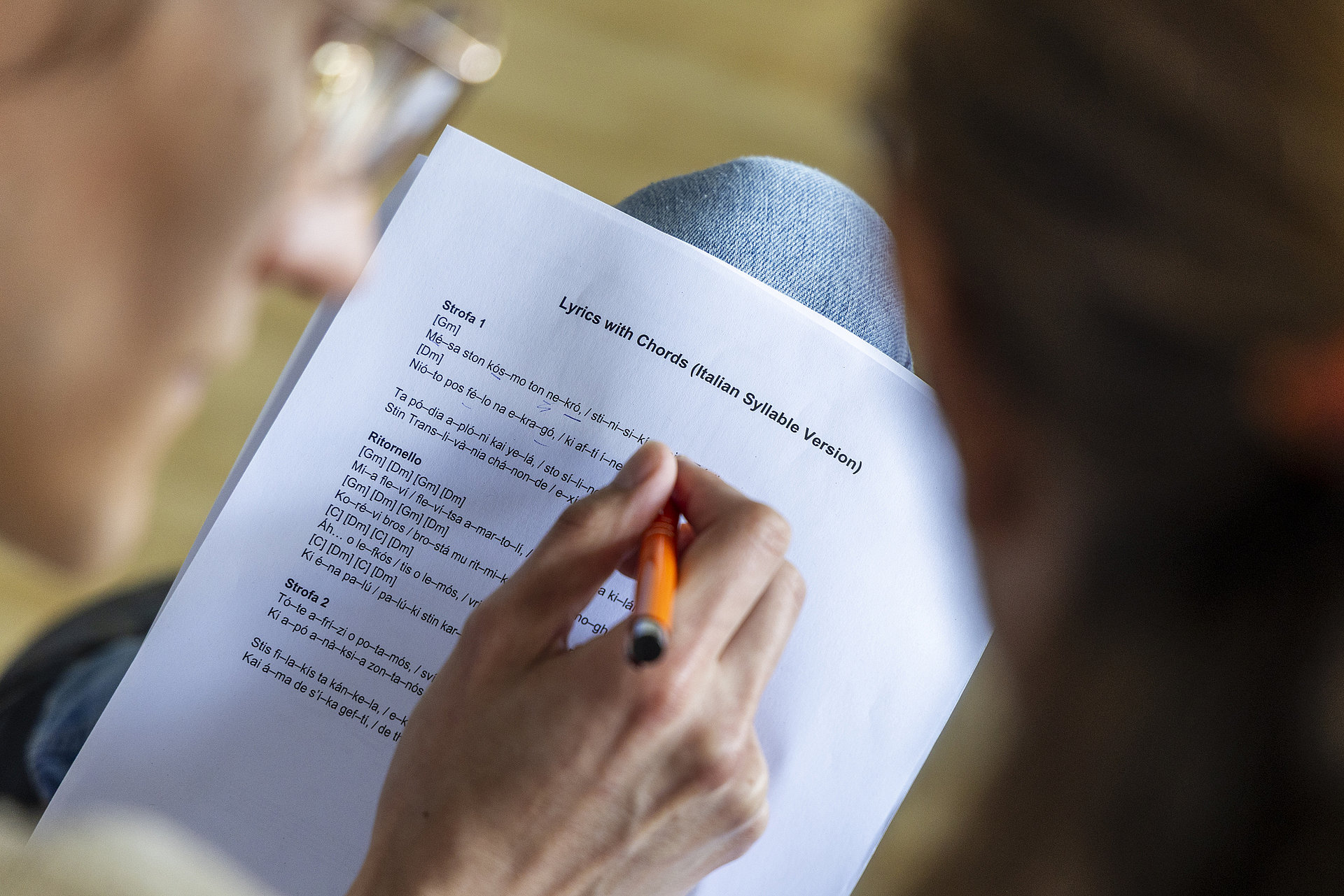 Blick über die Schulter eines Chorsängers auf ein Textblatt mit itaienischen Silben. 