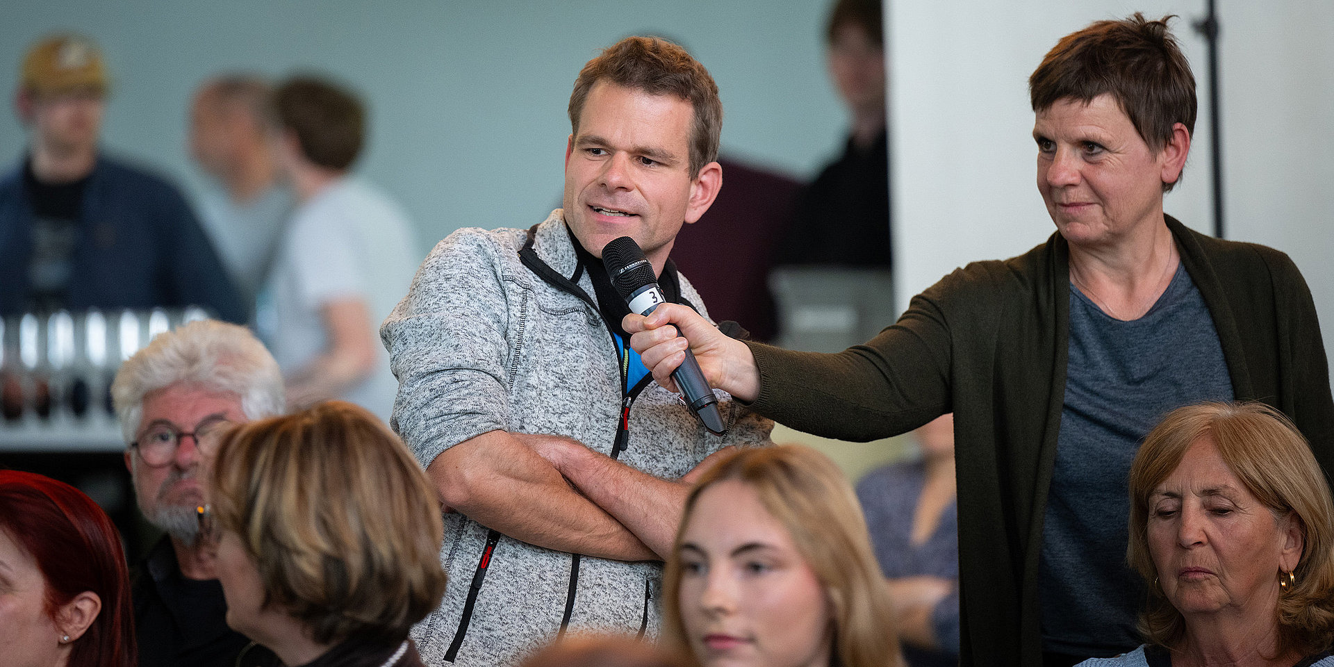 An h_da staff member holds out the hall microphone to a questioner.