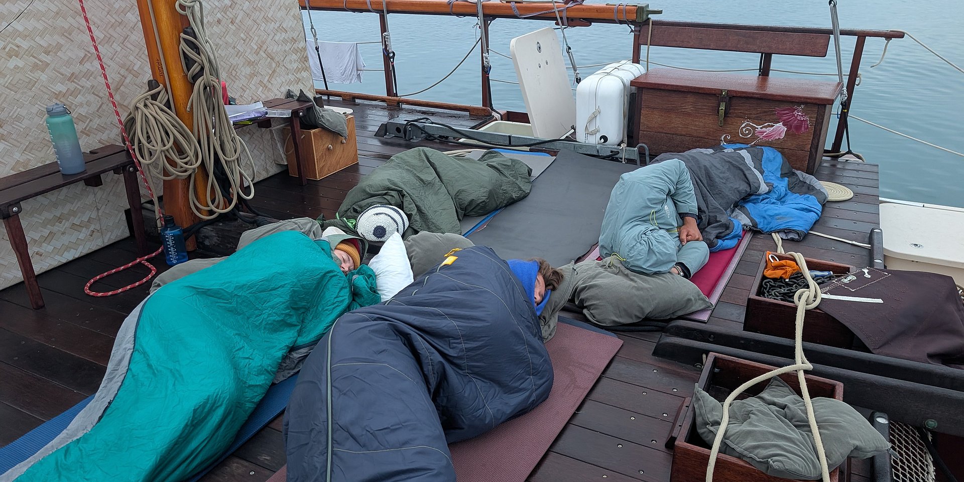Studenten kuschelten sich in Schlafsäcken auf einem Boot zusammen.