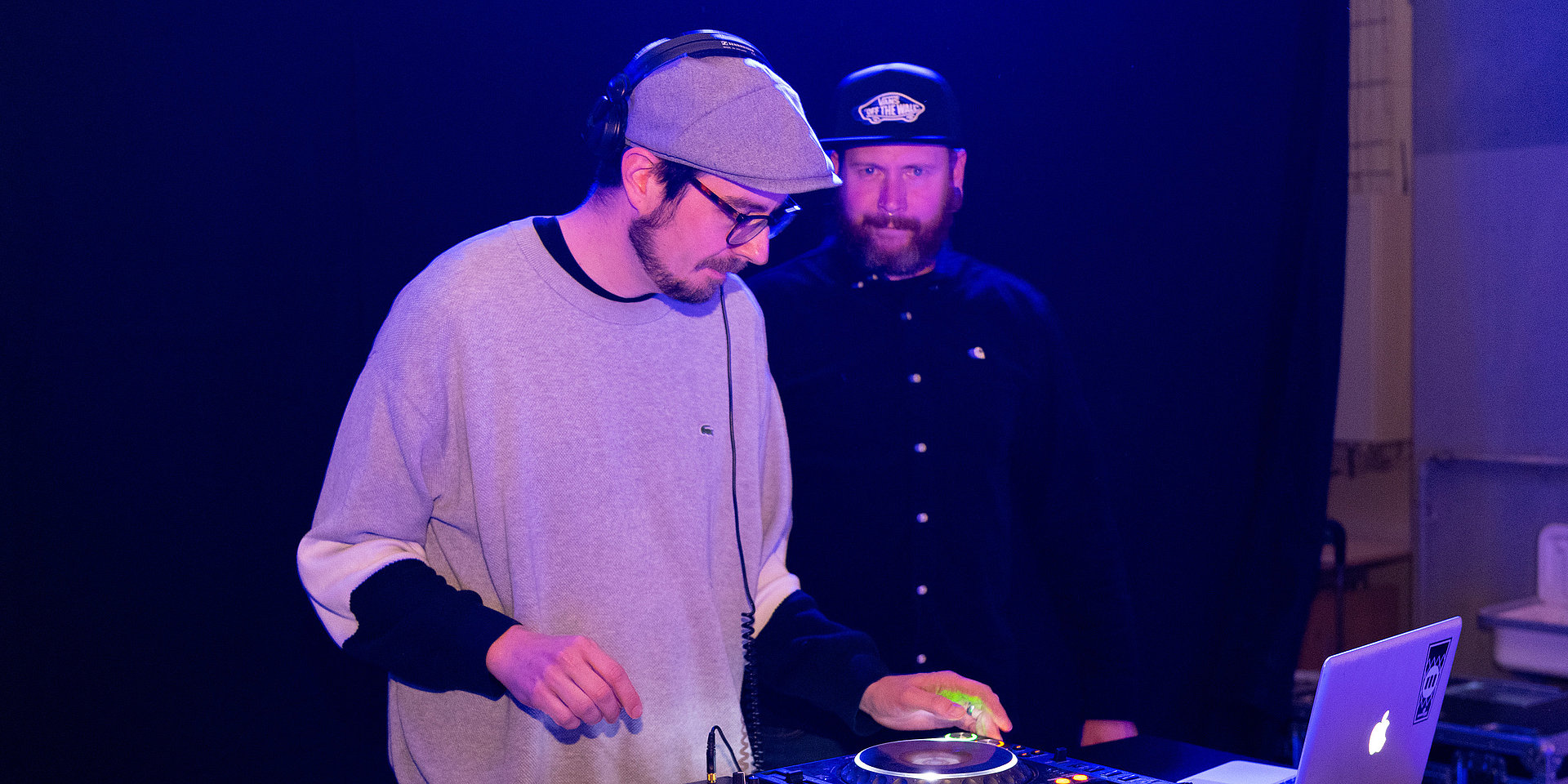 DJ mit Kopfhörern vor dem Mischpult.