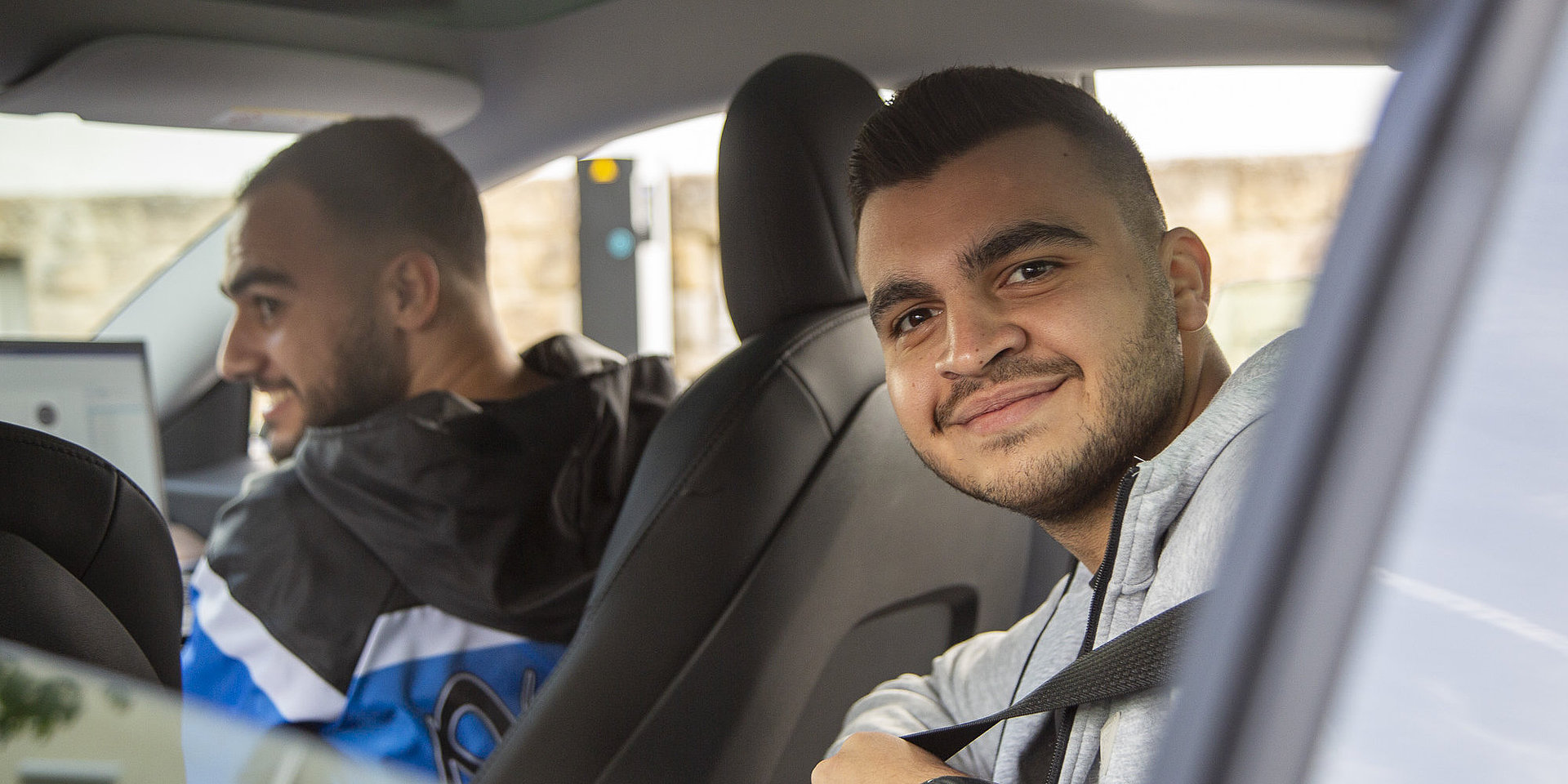 Ein Student sitzt in einem Auto und schaut in die Kamera.