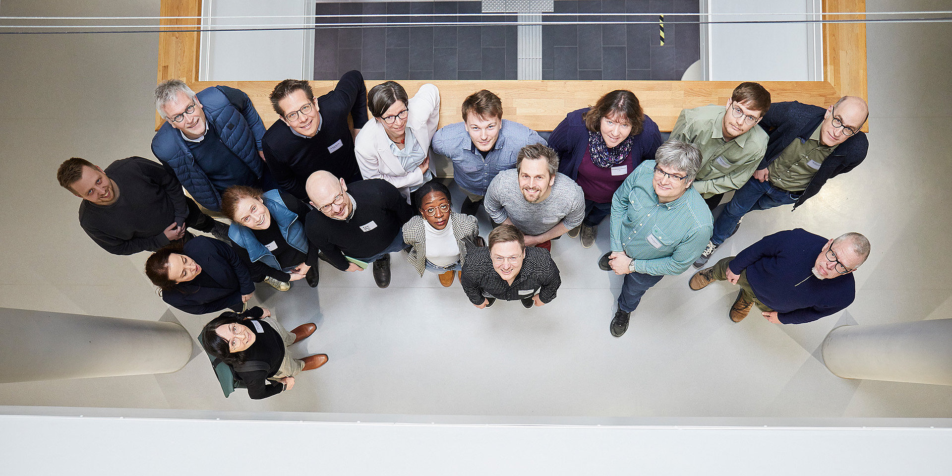 Gruppe von Workshop-Teilnehmenden im Erdgeschoss des CuB-Gebäudes mit Blick nach oben zum Fotografen