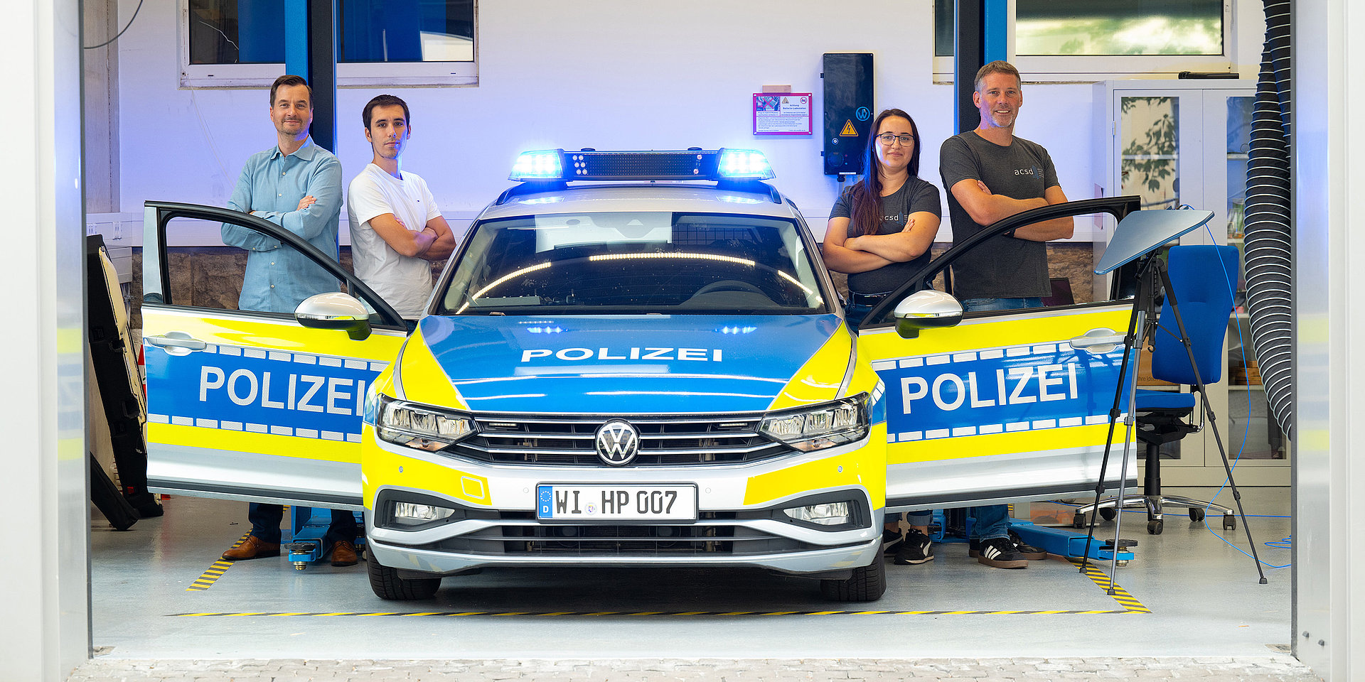 Das HECA Team der Hochschule Darmstadt steht um ein Polizeiauto herum.