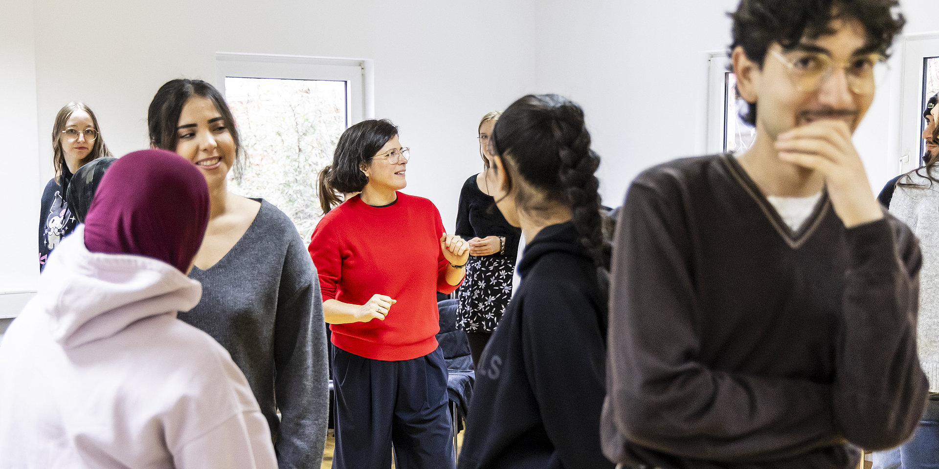 Gruppe von Studierenden steht im Workshopraum mit Trainerin in der Mitte.