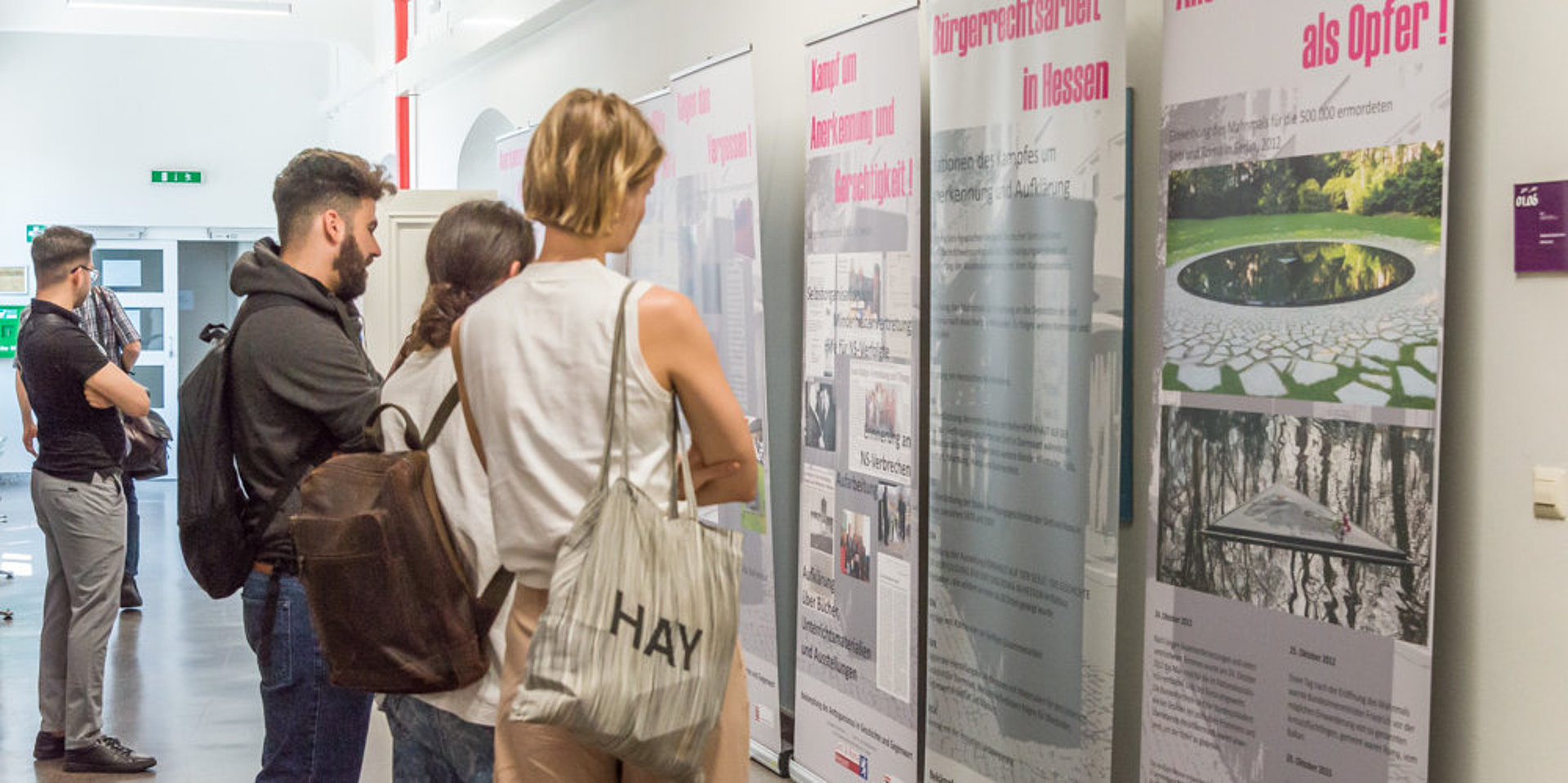 Besucher:innen lesen sich die Plakate der Ausstellung "Der Weg der Sinti und Roma" durch.