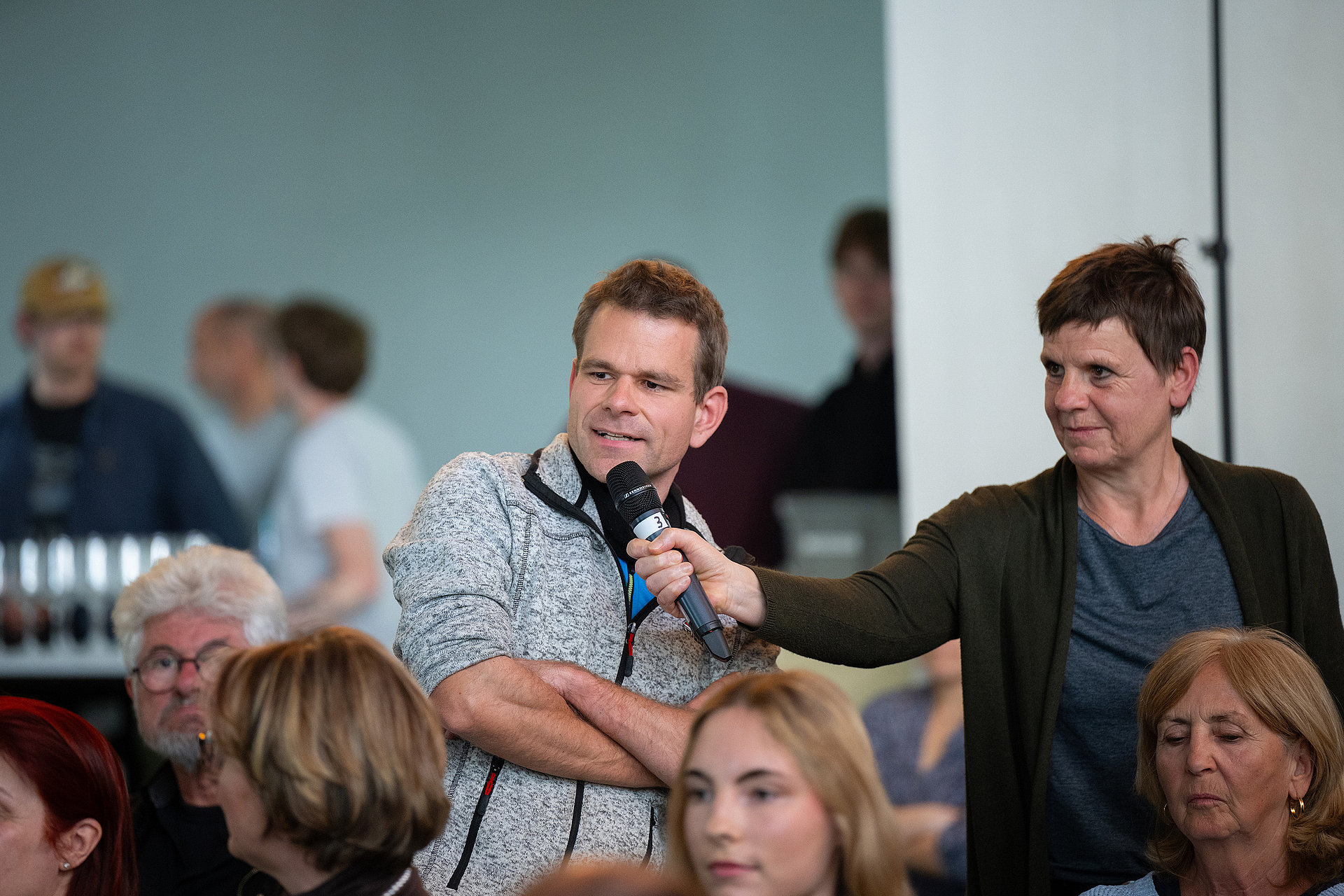 An h_da staff member holds out the hall microphone to a questioner.