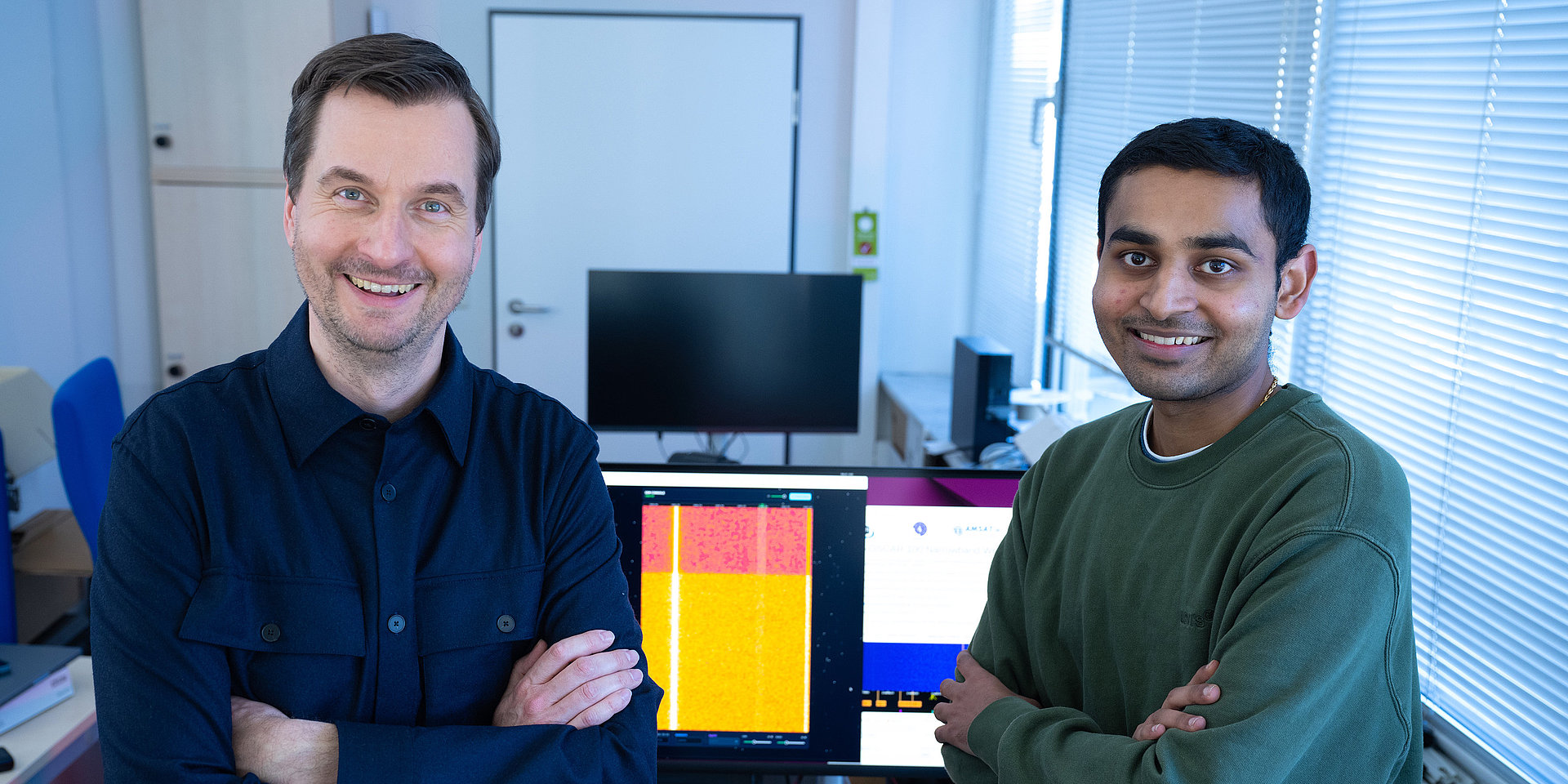 Student Vedant Vedant and Professor Stefan Valentin are pictured standing next to each other and smiling into the camera.