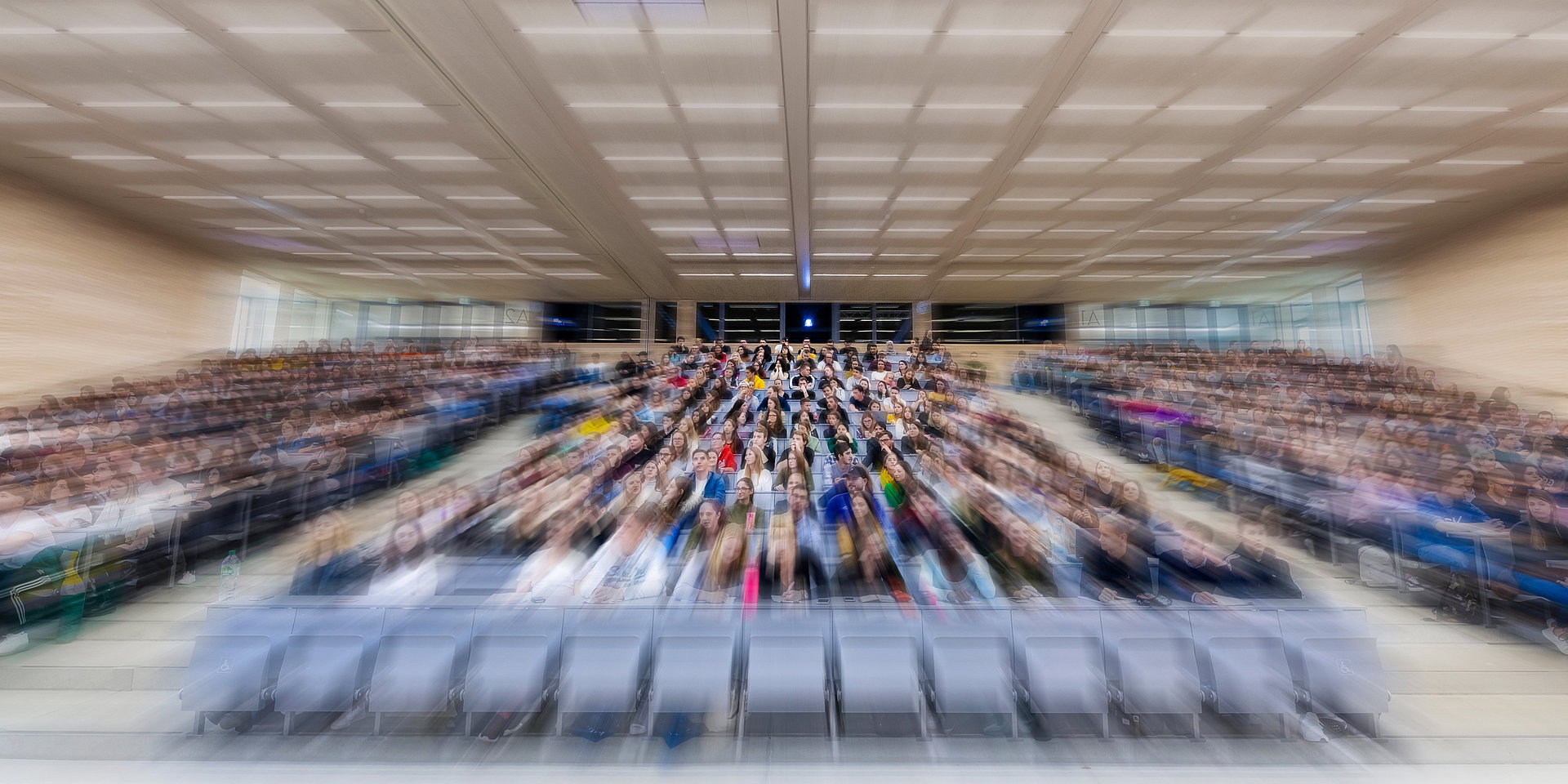 Verzerrtes Bild eines vollen Vorlesungsraumes.