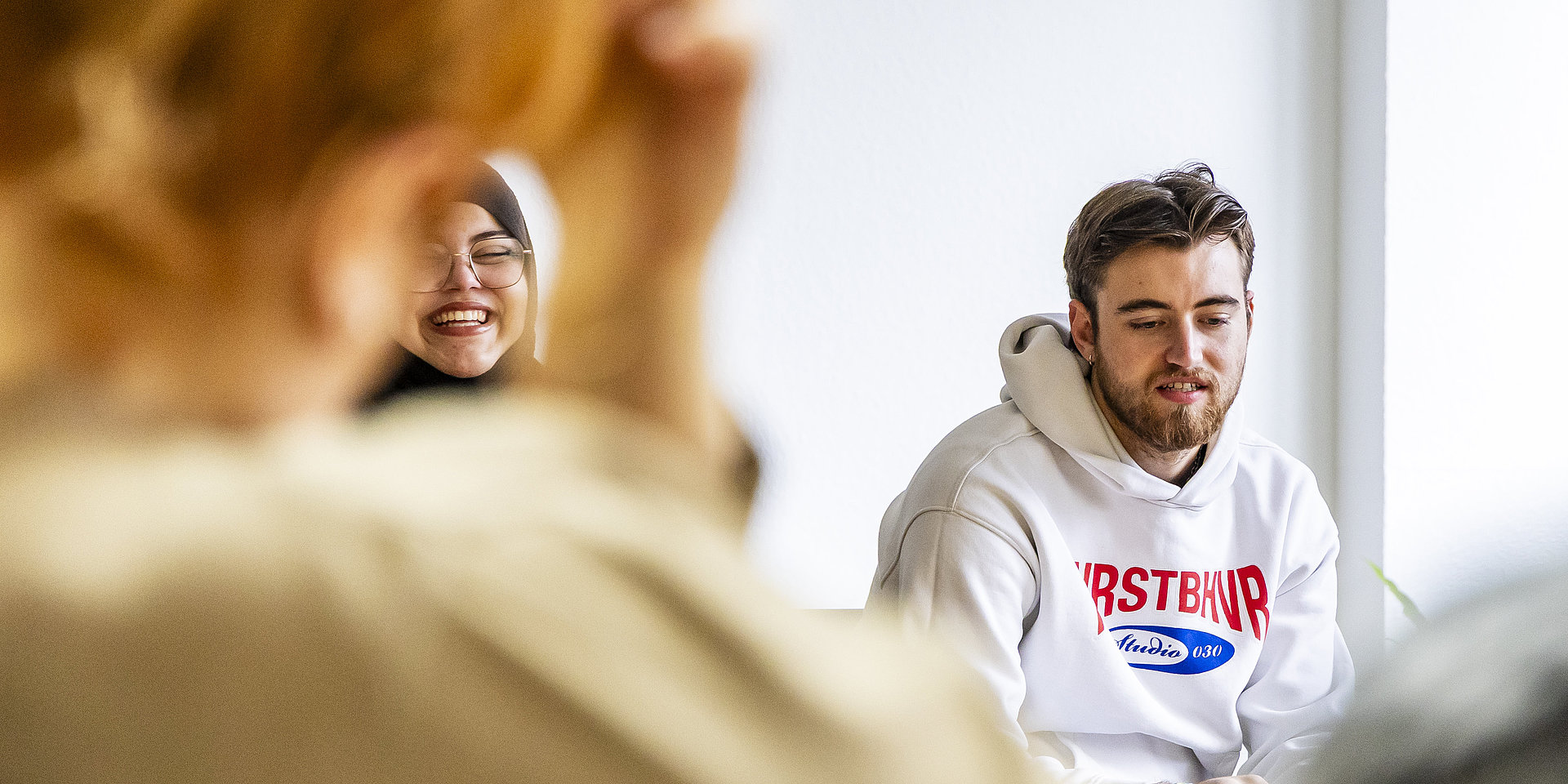 Zwei Studierende, ein junger Mann und eine junge Frau, in einer Diskussionsrunde.
